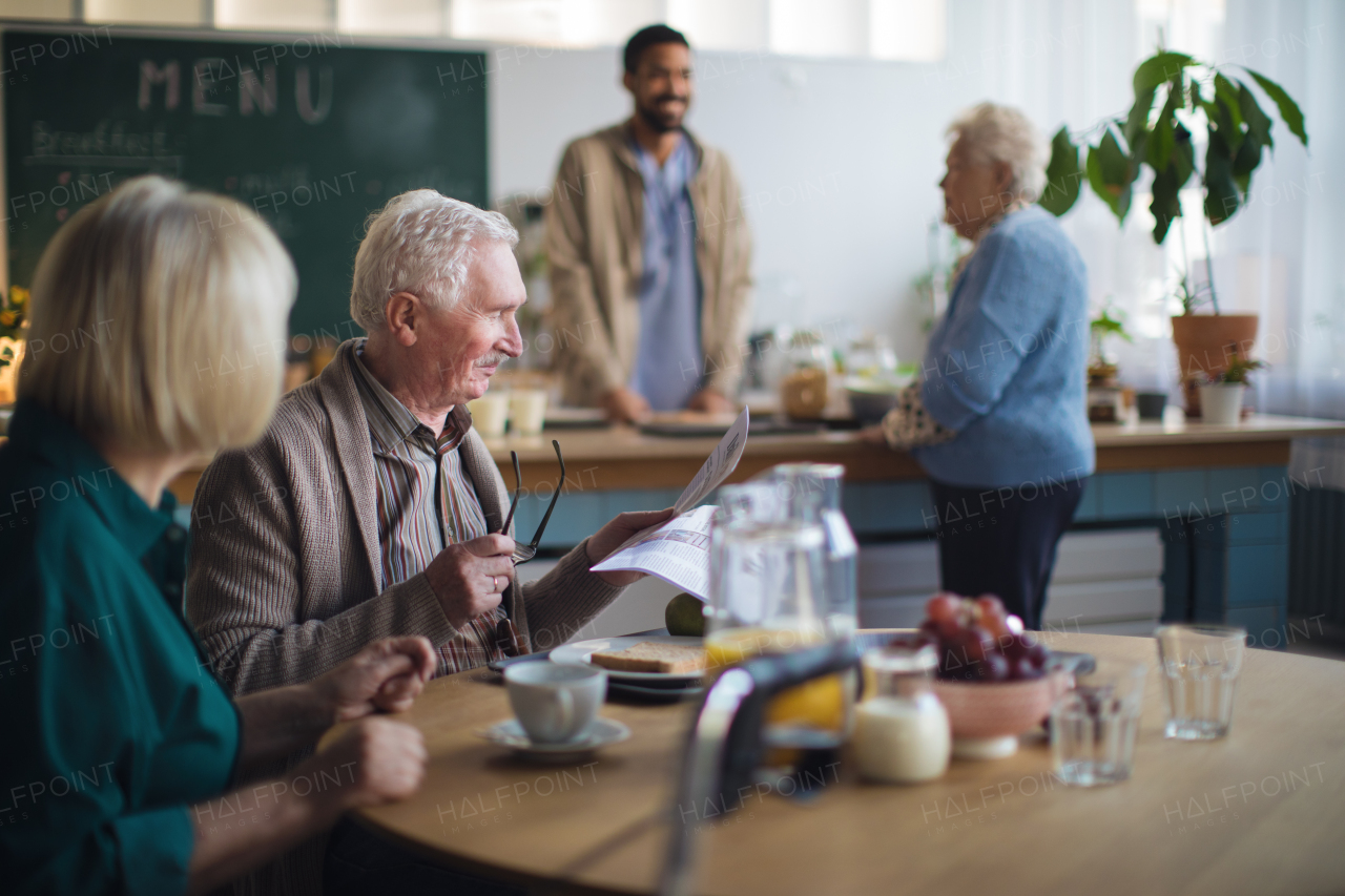 A smiling elderly woman and man enjoying breakfast in nursing home care center.