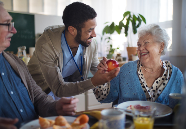 A smiling elderly woman and man enjoying breakfast in nursing home care center.