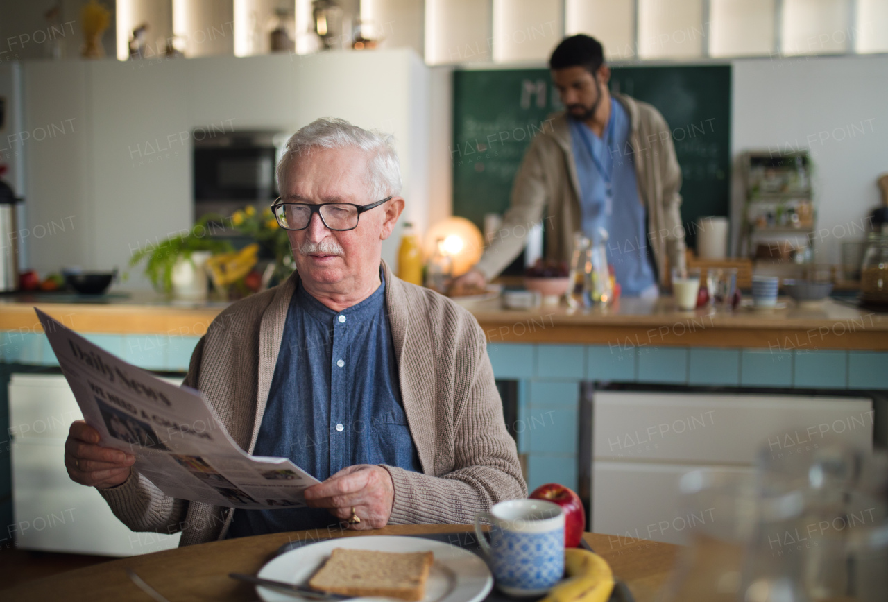 An elderly man enjoying breakfast and reading newspaper in nursing home care center.