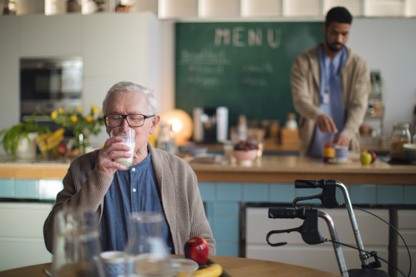 A smiling elderly man enjoying breakfast in nursing home care center.