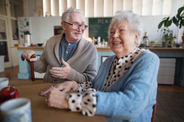 A smiling elderly woman and man enjoying breakfast in nursing home care center.