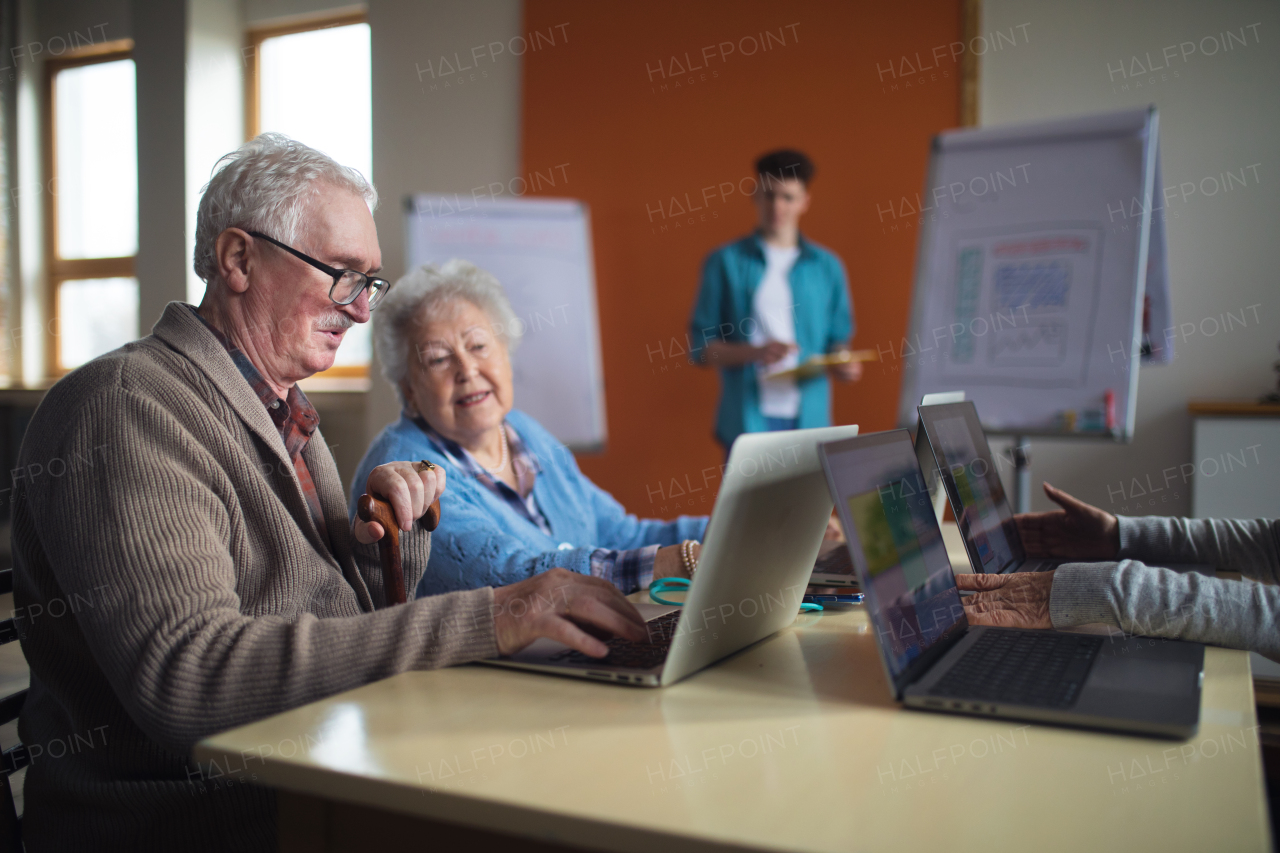 A senior group in retirement home with young instructor learning together in computer class