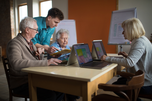 A senior group in retirement home with young instructor learning together in computer class