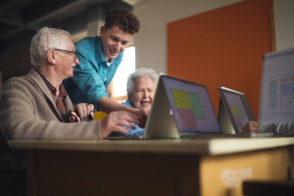 A senior group in retirement home with young instructor learning together in computer class