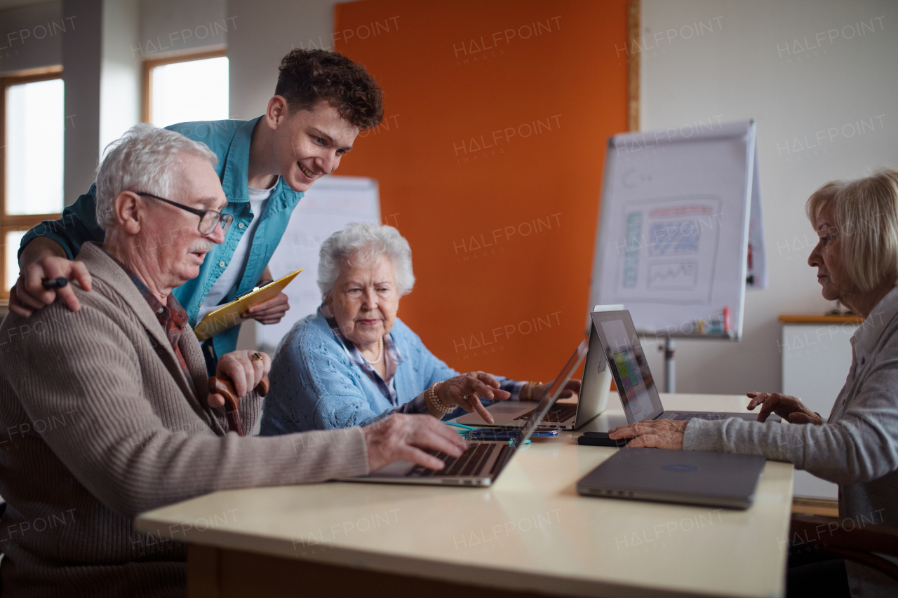 A senior group in retirement home with young instructor learning together in computer class