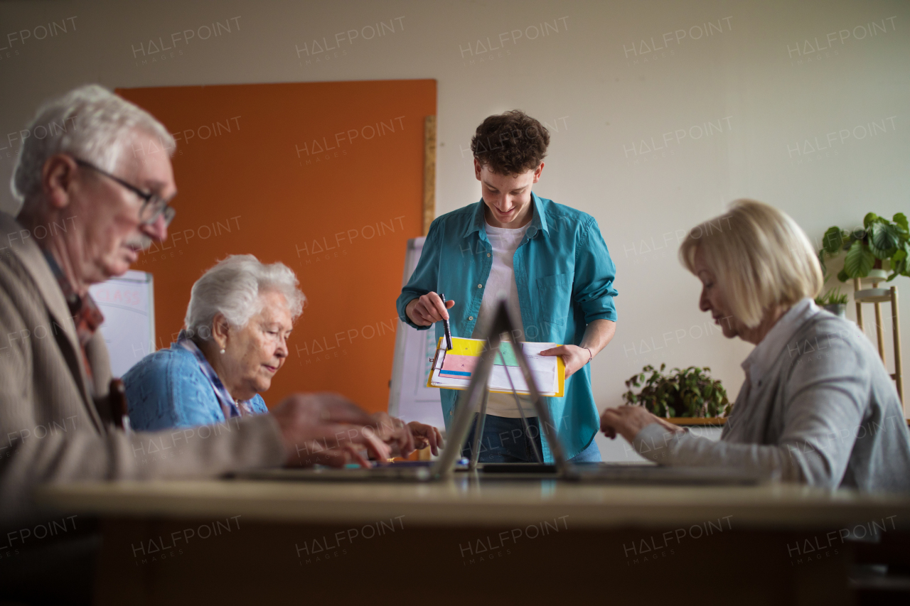 A senior group in retirement home with young instructor learning together in computer class