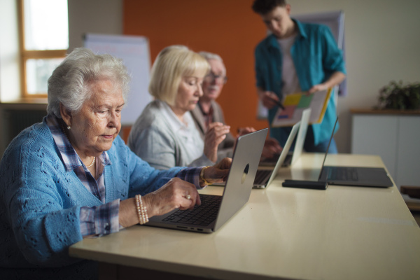 A senior group in retirement home with young instructor learning together in computer class