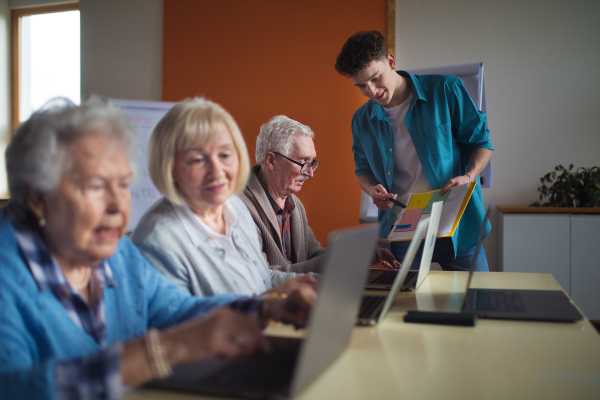 A senior group in retirement home with young instructor learning together in computer class