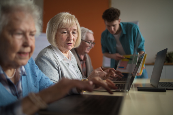 A senior group in retirement home with young instructor learning together in computer class