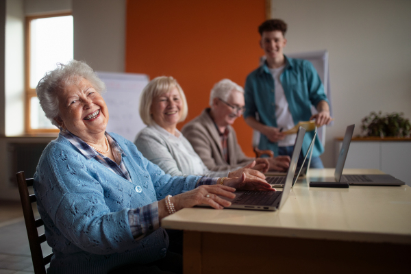 A senior group in retirement home with young instructor learning together in computer class