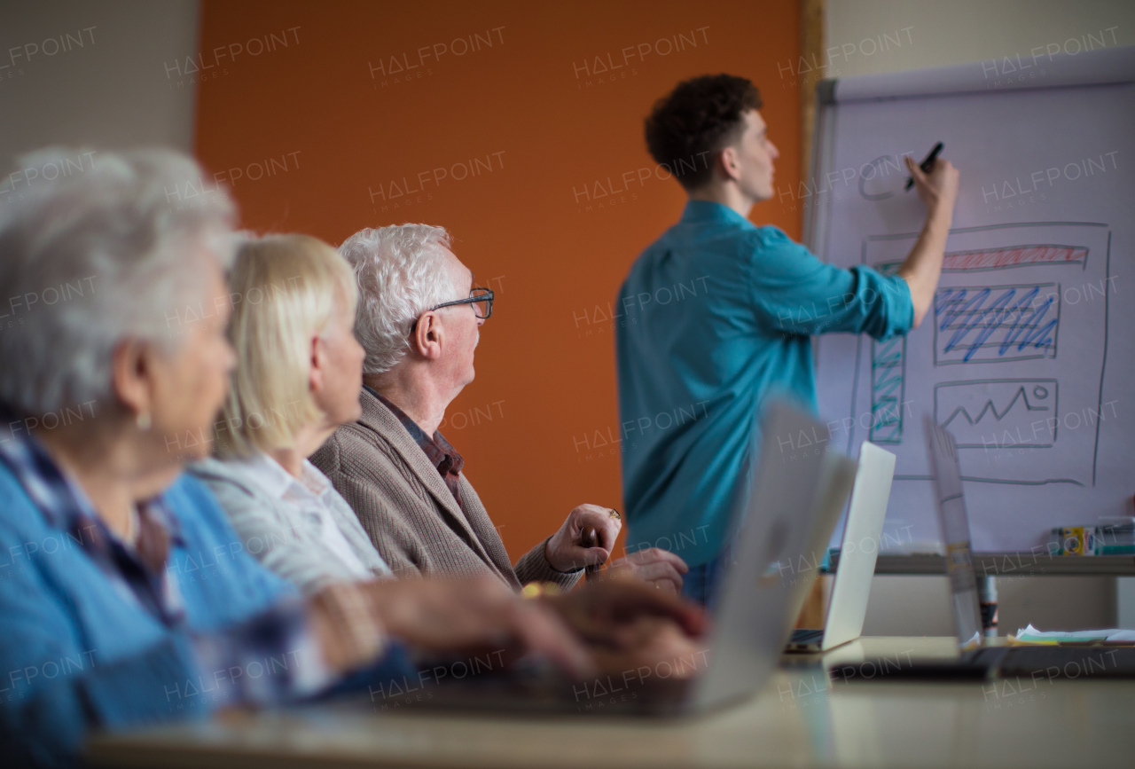 A senior group in retirement home with young instructor learning together in computer class