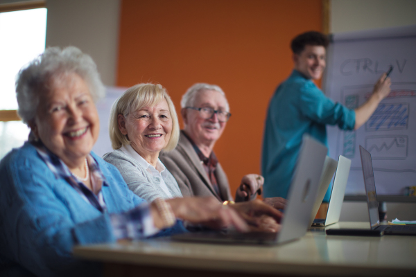 A senior group in retirement home with young instructor learning together in computer class