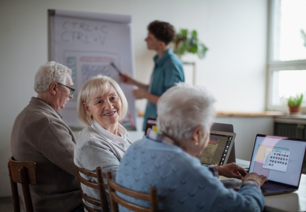 A senior group in retirement home with young instructor learning together in computer class