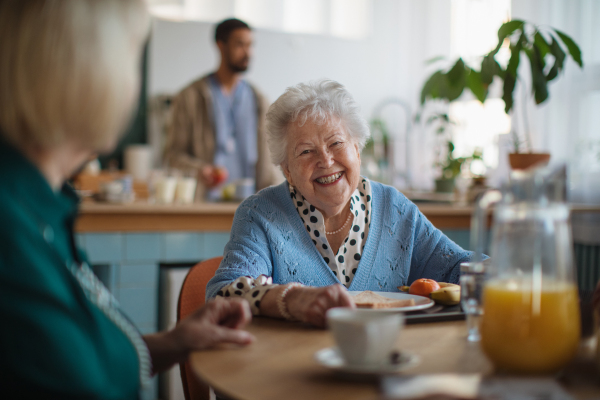 A smiling elderly woman enjoying breakfast in nursing home care center.