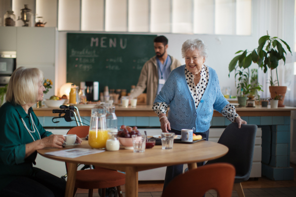 Smiling elderly women enjoying breakfast in a nursing home care center.