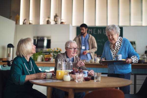 A group of cheerful seniors enjoying breakfast in nursing home care center.