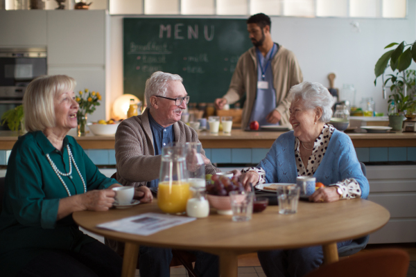 A group of cheerful seniors enjoying breakfast in nursing home care center.