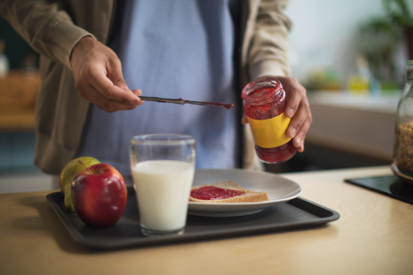 A close-up of caregiver preparing breakfast in nursing home for seniors.