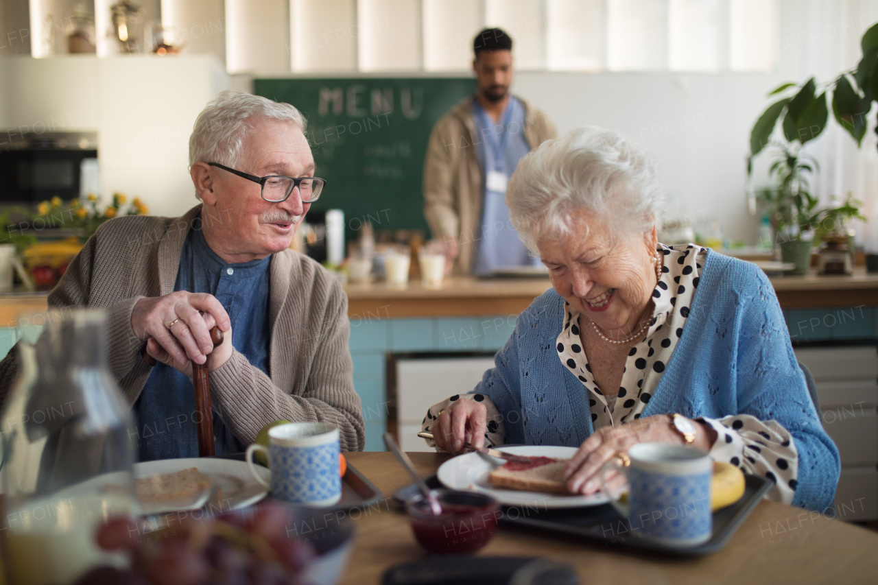 A smiling elderly woman and man enjoying breakfast in nursing home care center.