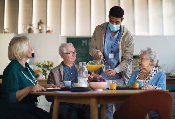 A group of cheerful seniors enjoying breakfast in nursing home care center.