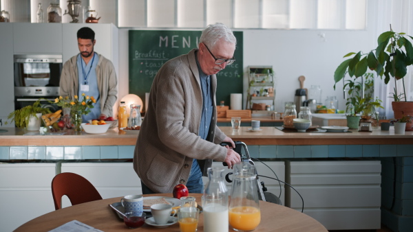 A smiling elderly man enjoying breakfast in nursing home care center.