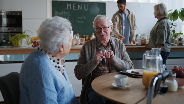 A smiling elderly woman and man enjoying breakfast in nursing home care center.