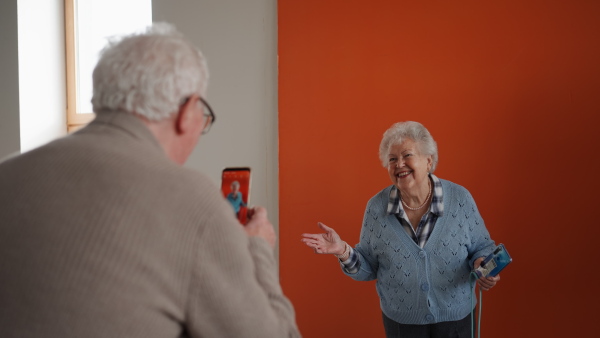 A senior man taking a picture of her friend during computer class.