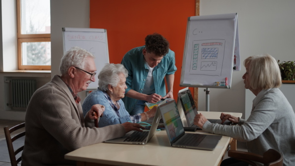 A senior group in retirement home with young instructor learning together in computer class