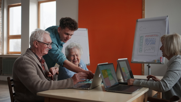 A senior group in retirement home with young instructor learning together in computer class