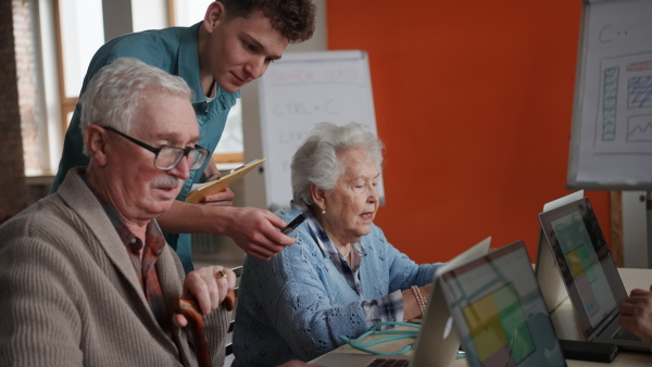 A senior group in retirement home with young instructor learning together in computer class