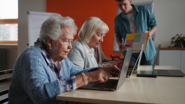 A senior group in retirement home with young instructor learning together in computer class