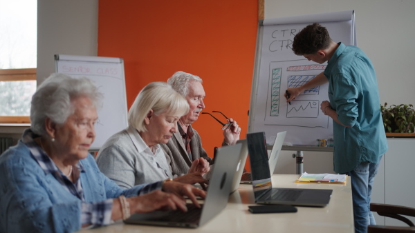 A senior group in retirement home with young instructor learning together in computer class