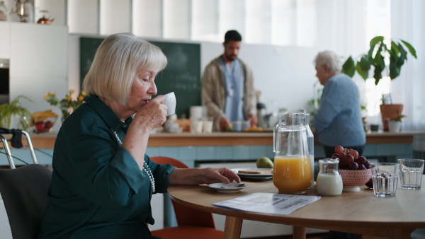 A smiling elderly woman enjoying breakfast in nursing home care center.