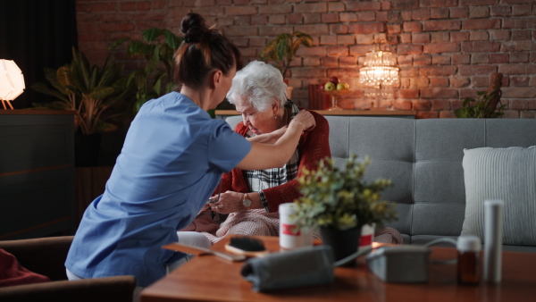 A female healthcare worker or caregiver visiting senior woman indoors at home, doing body care to patient.