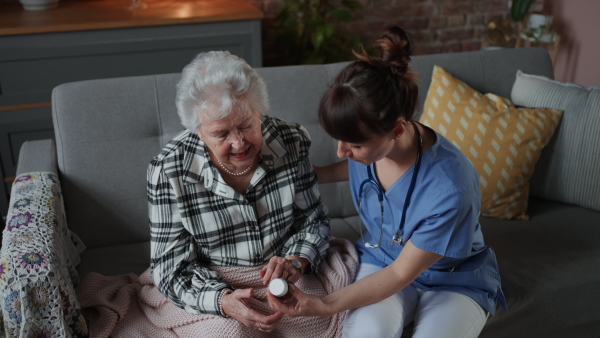 A female doctor doing check up to senior woman indoors at home during home visit, explaining dosage.