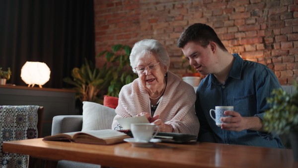 Grandmother with Down Syndrome Adult looking at photograph, drinking tea