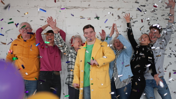 A diverse group of cheerful people standing together and celebrating with confetti