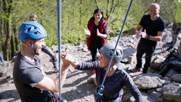 A group of seniors with instructor celebrating successful rocks climbing outdoors in nature, active lifestyle.