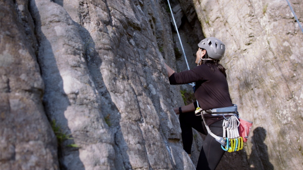 Portrait of senior woman climbing rocks outdoors in nature, active lifestyle.