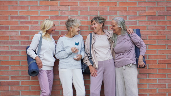 A cheerful group of senior women talking after exercise outdoors in street