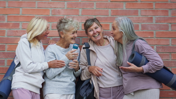 A cheerful group of senior women talking after exercise outdoors in street