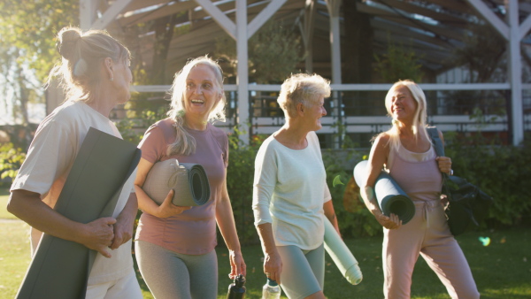 Senior women friends walking together after exercise outdoors in a park.