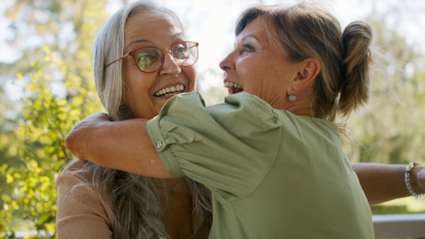 A happy senior woman getting present from friend during celebration outdoors on patio