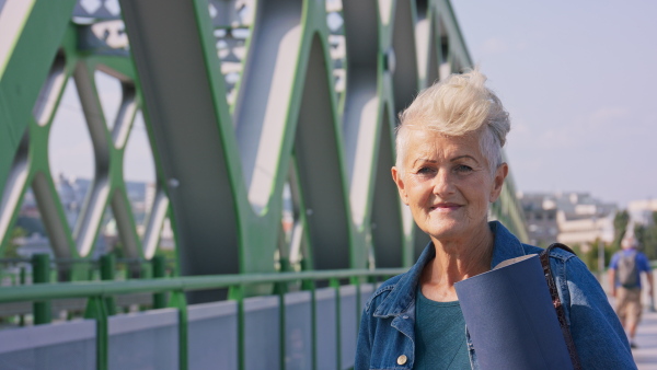 A happy senior woman going on sport session to city park, looking at camera.