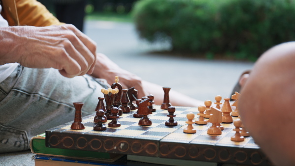 A close-up of senior men friends sitting outdoors in city, playing chess.