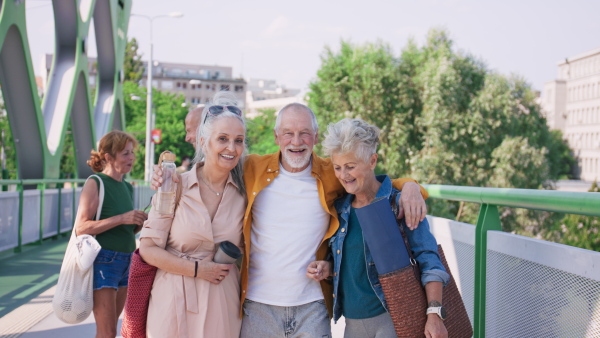 A group of happy senior friends going on sport session to city park, looking at camera.