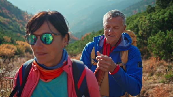 A senior couple hikers having break and drinking water in mountains.