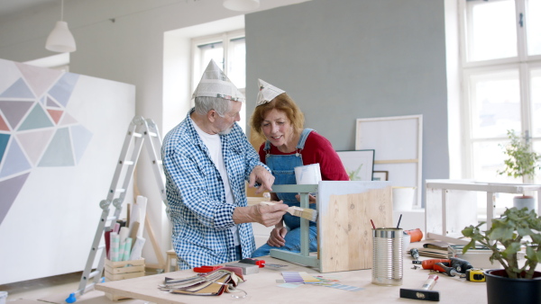 Beautiful senior couple renovating old wooden furniture.