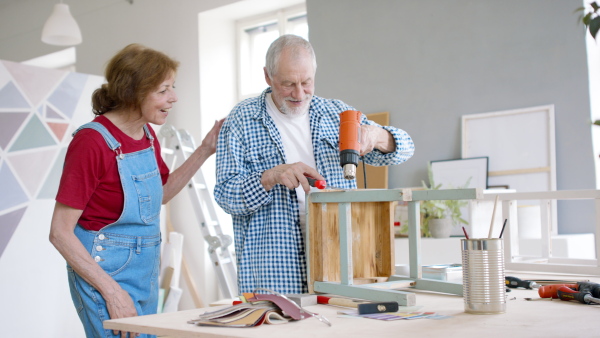 Beautiful senior couple renovating old wooden furniture.