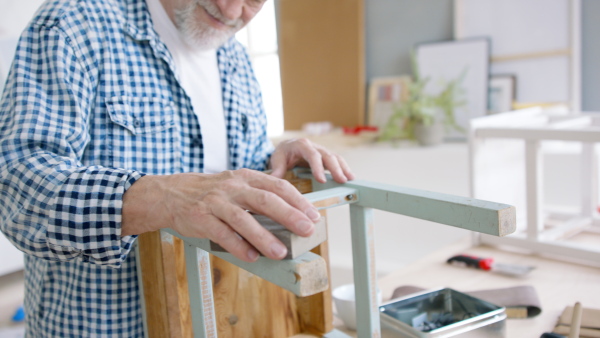 Unrecognizable senior man renovating old wooden furniture.